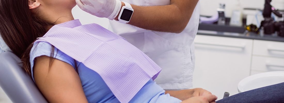 Dentist examining female patient teeth in clinic