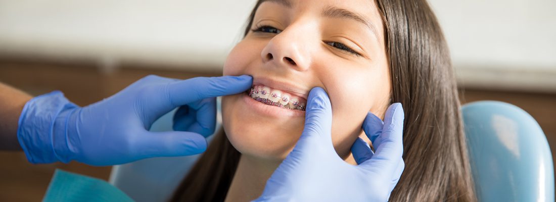 Teenage girl with braces being examined by dentist wearing gloves at clinic